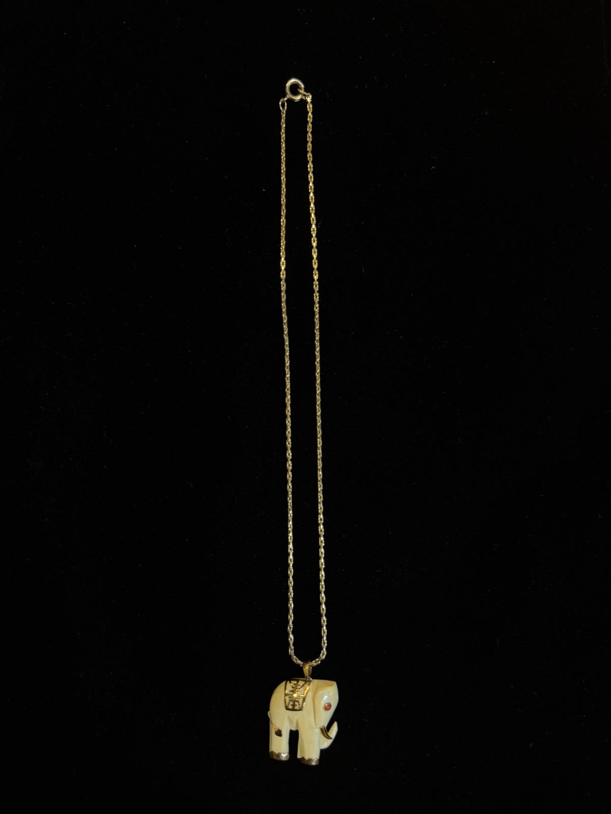 Gold elephant pendant necklace on a black background
