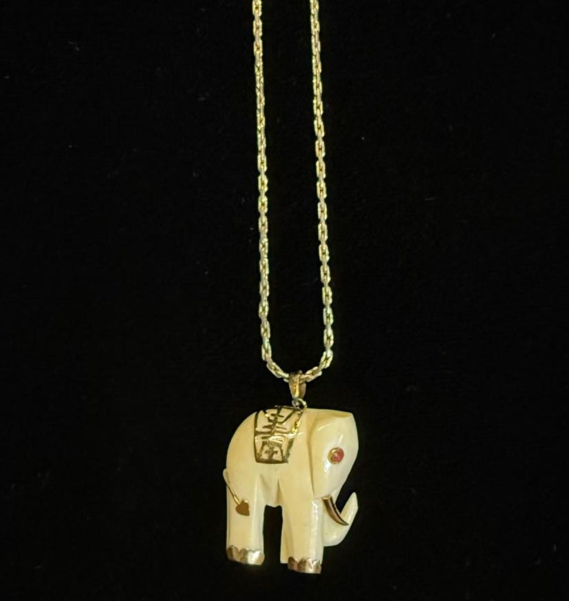 Gold elephant pendant necklace on a black background