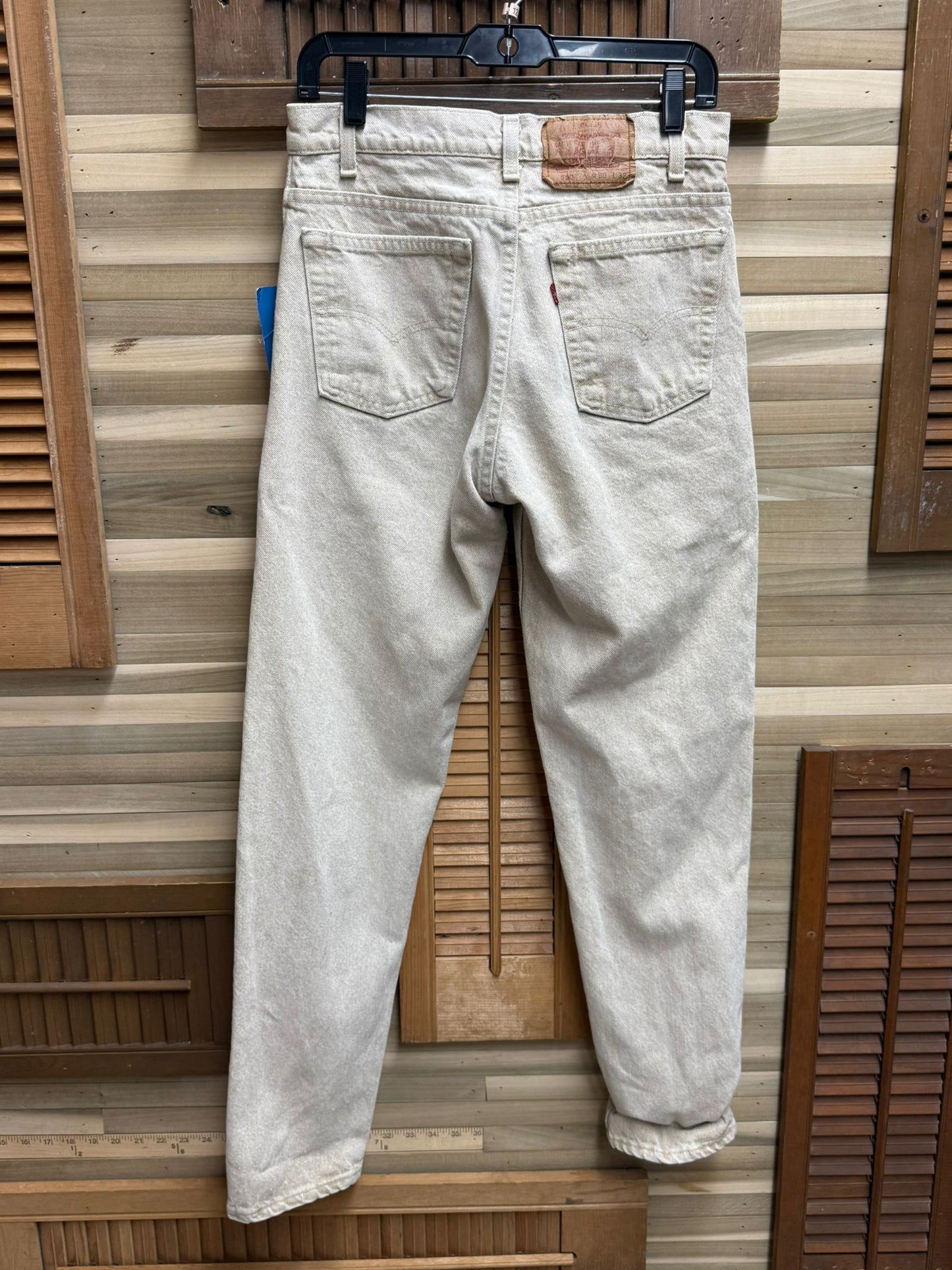 Light-colored jeans hanging against a wooden panel background