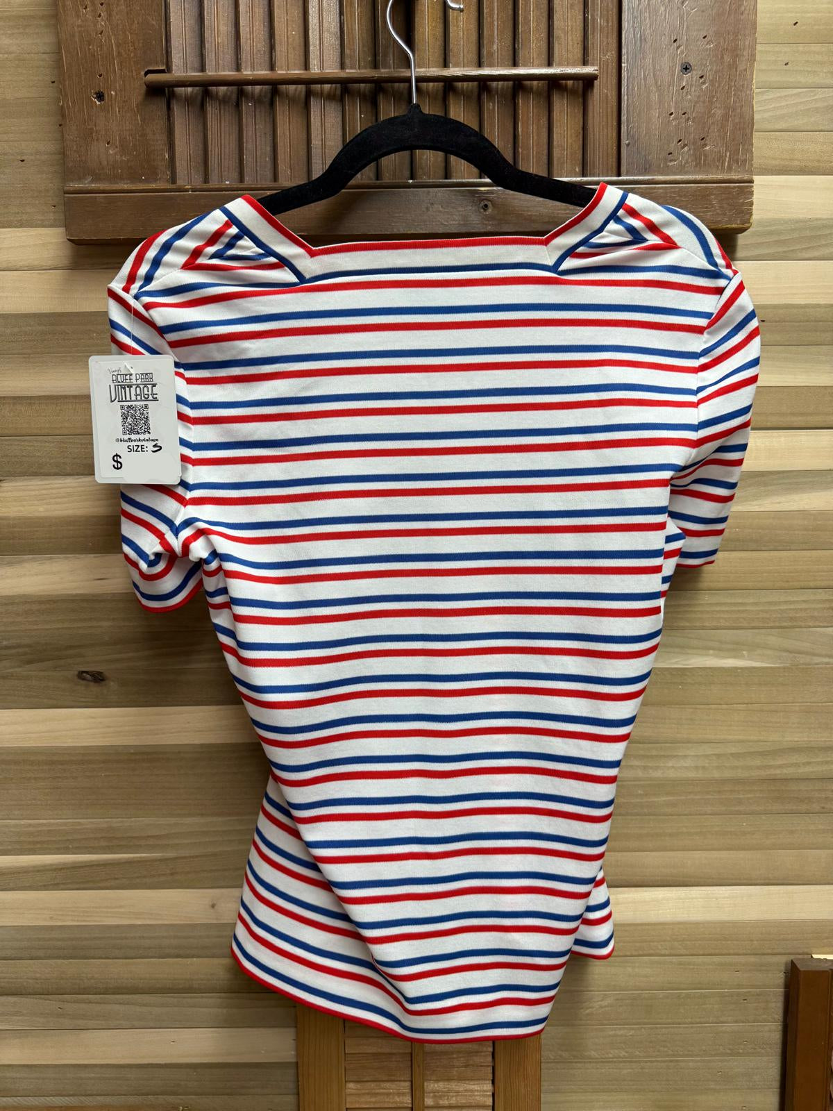 Red, white, and blue striped dress on a hanger against a wooden background