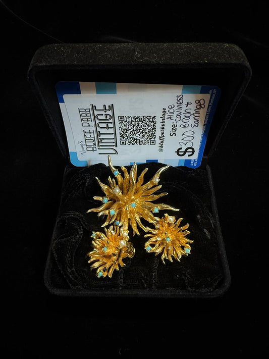 Gold floral earrings with turquoise stones in a display case, branded 'Blue Pearl Vintage'.