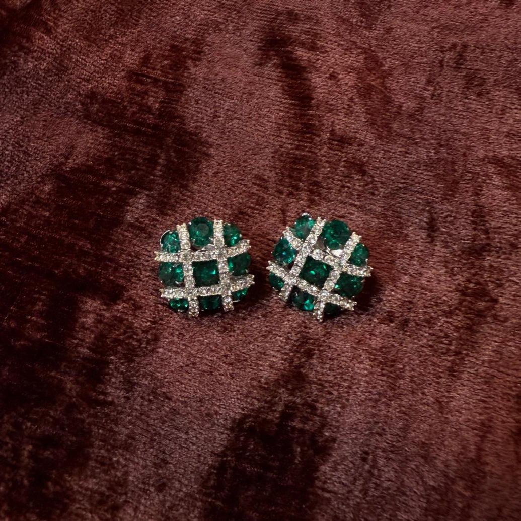 Pair of green gemstone earrings on a brown textured surface