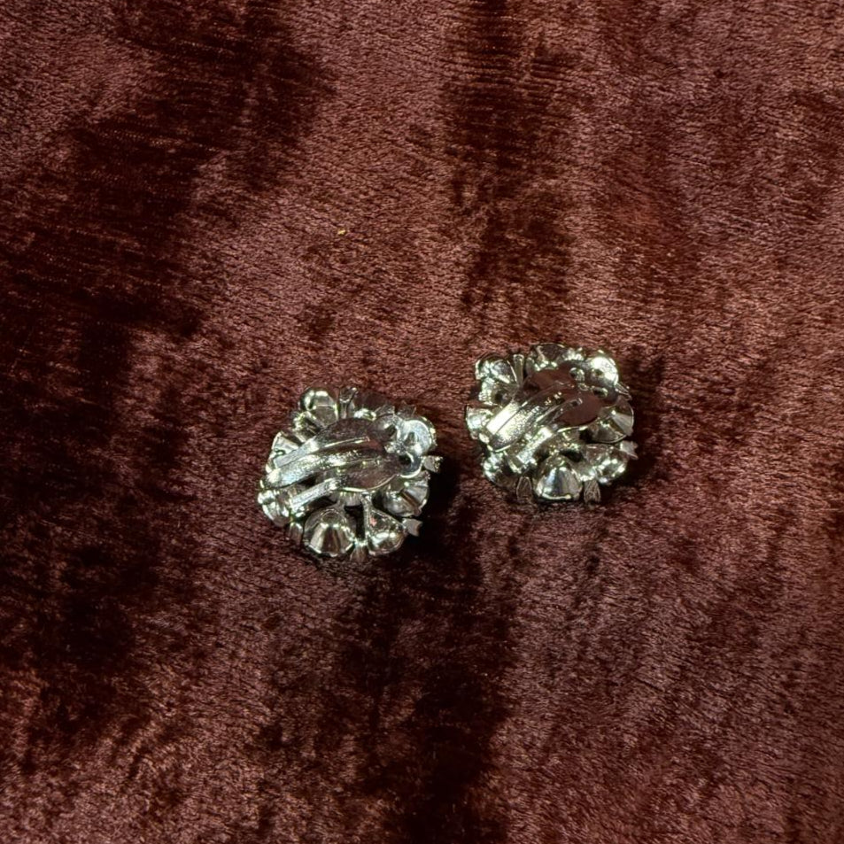 Pair of silver rhinestone earrings on a brown velvet background