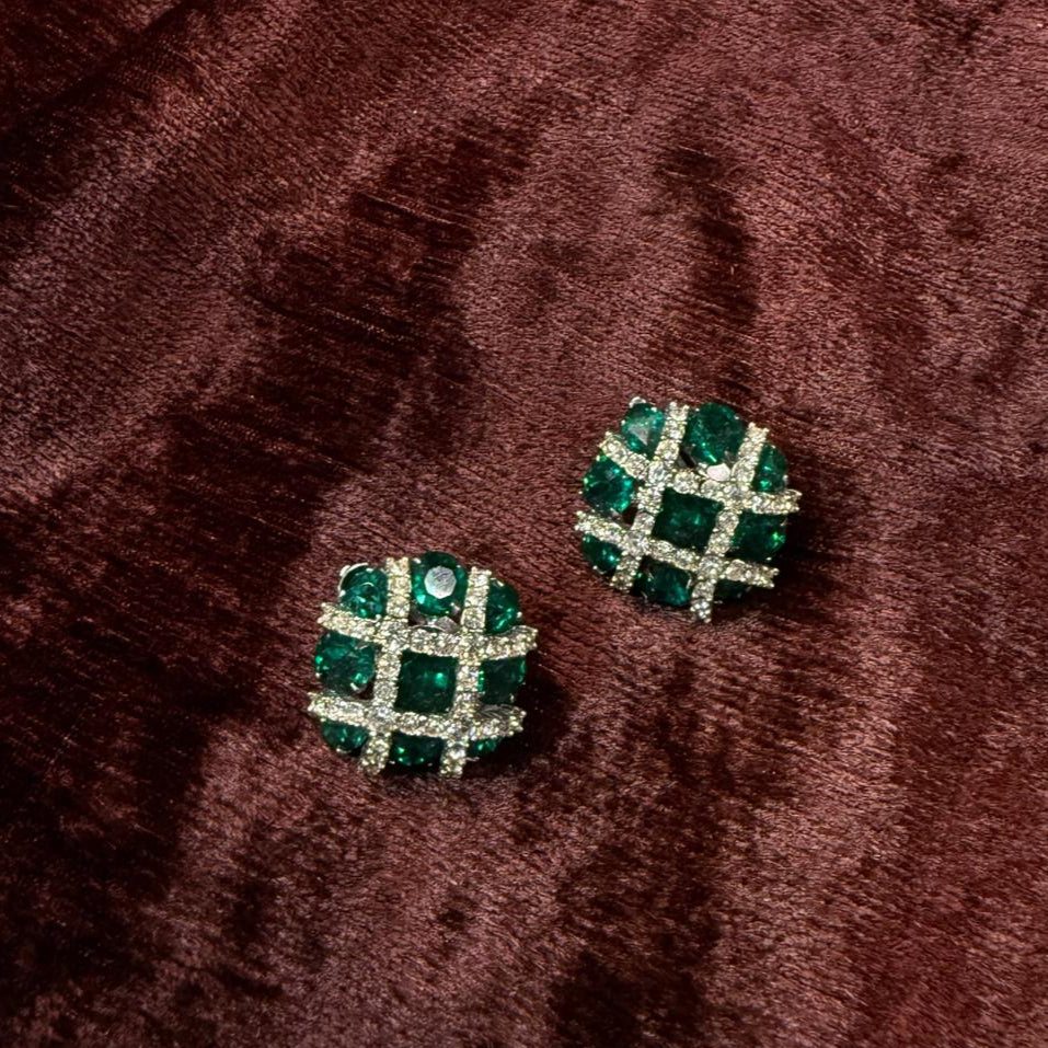 Green checkered earrings on a brown textured fabric background