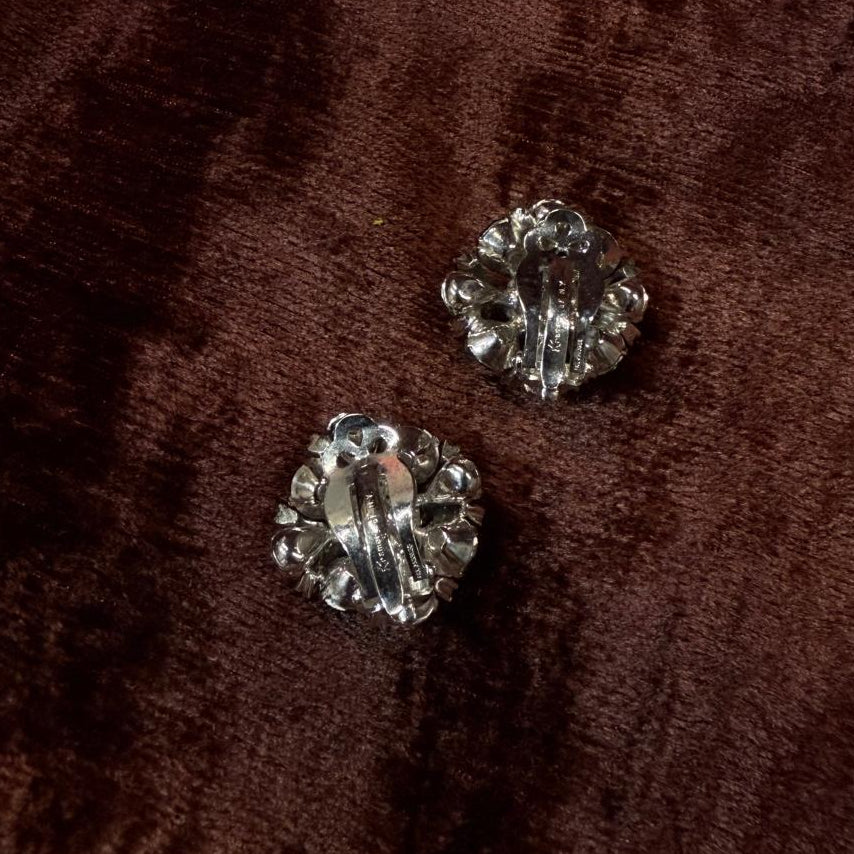 Silver earrings on a brown textured fabric background