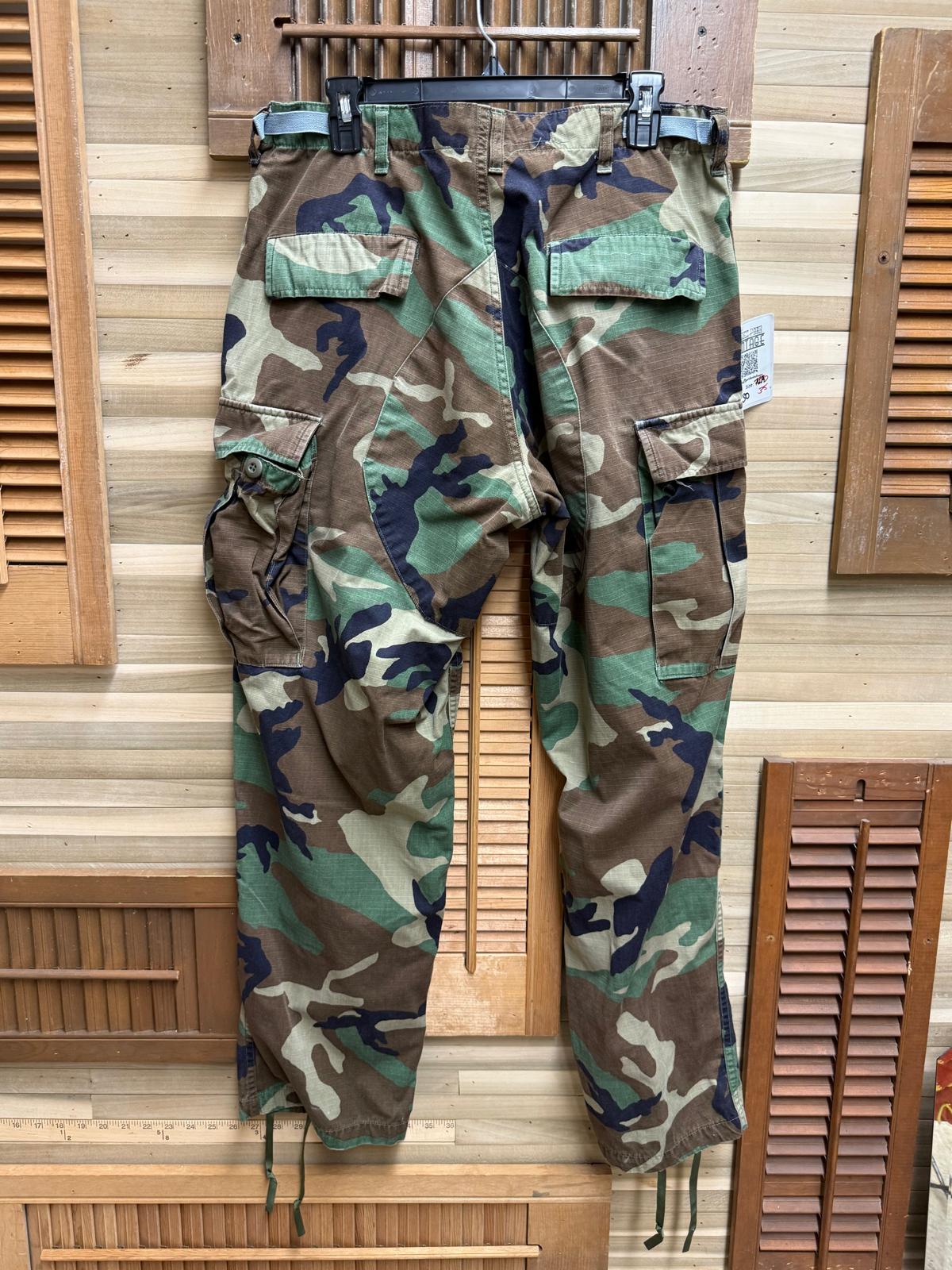 Camouflage pants hanging on a wooden rack with shutters in the background