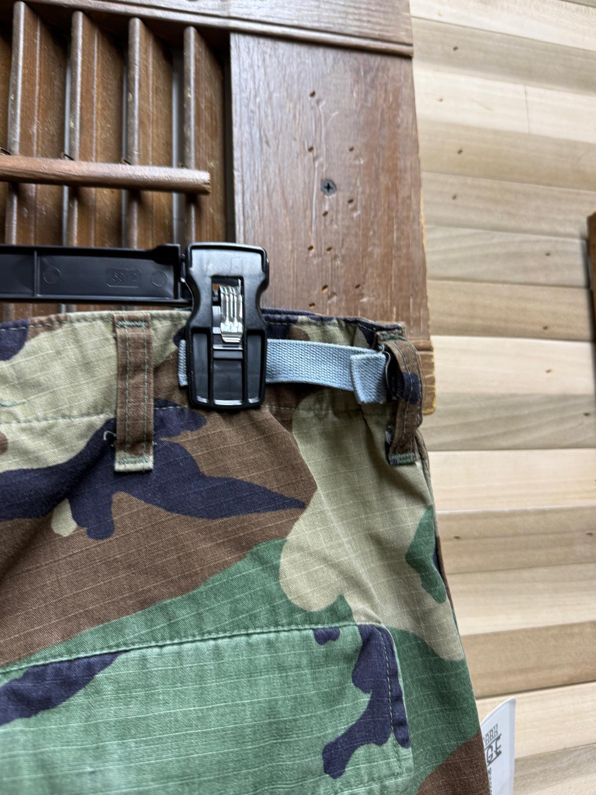 Camouflage pants with a black belt buckle on a wooden background