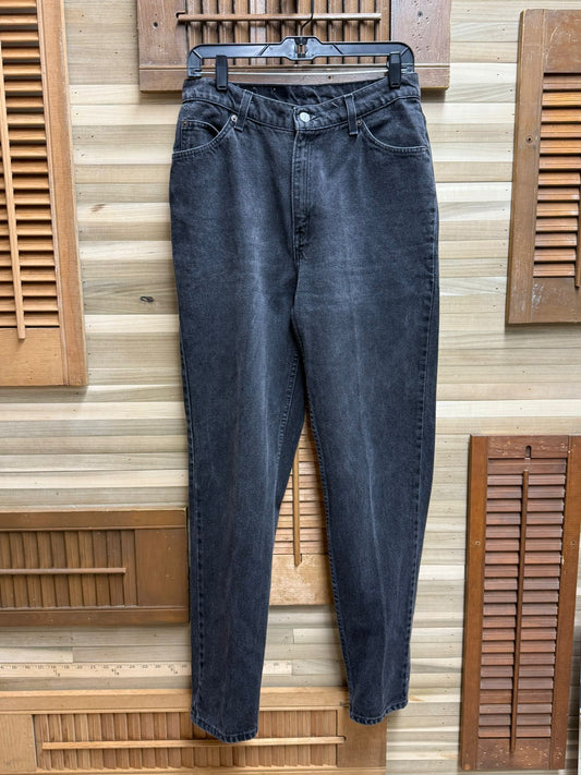 Black jeans hanging on a wooden hanger against a wooden panel background