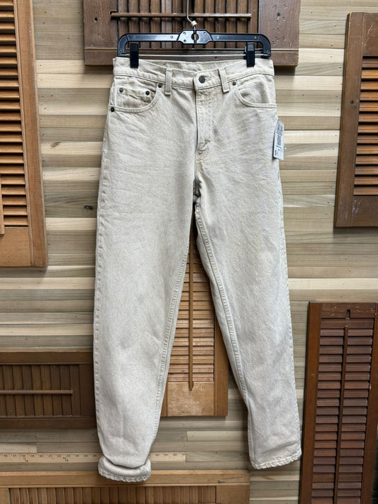 Light-colored jeans hanging on a wooden hanger against a wooden panel background