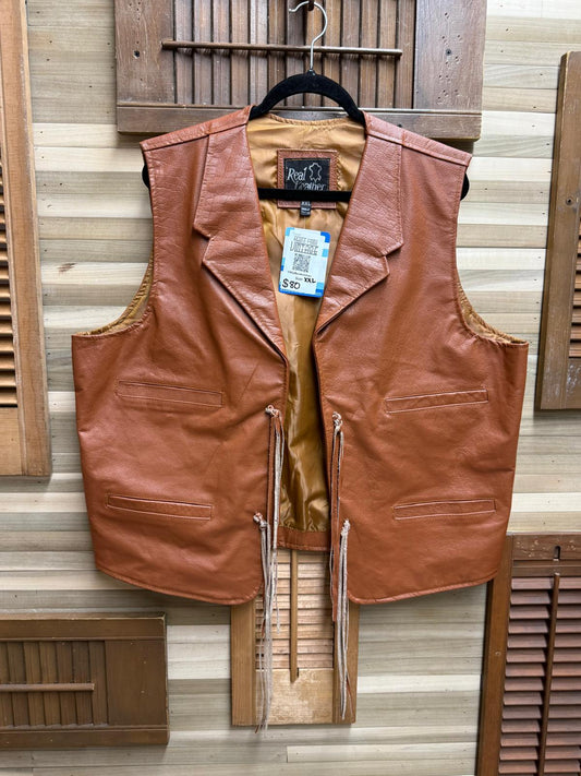 Brown leather vest on a hanger against a wooden panel background